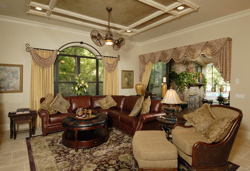 Living room with leather sectional sofa, tufted ottoman coffee table, fireplace, and coffered ceiling.