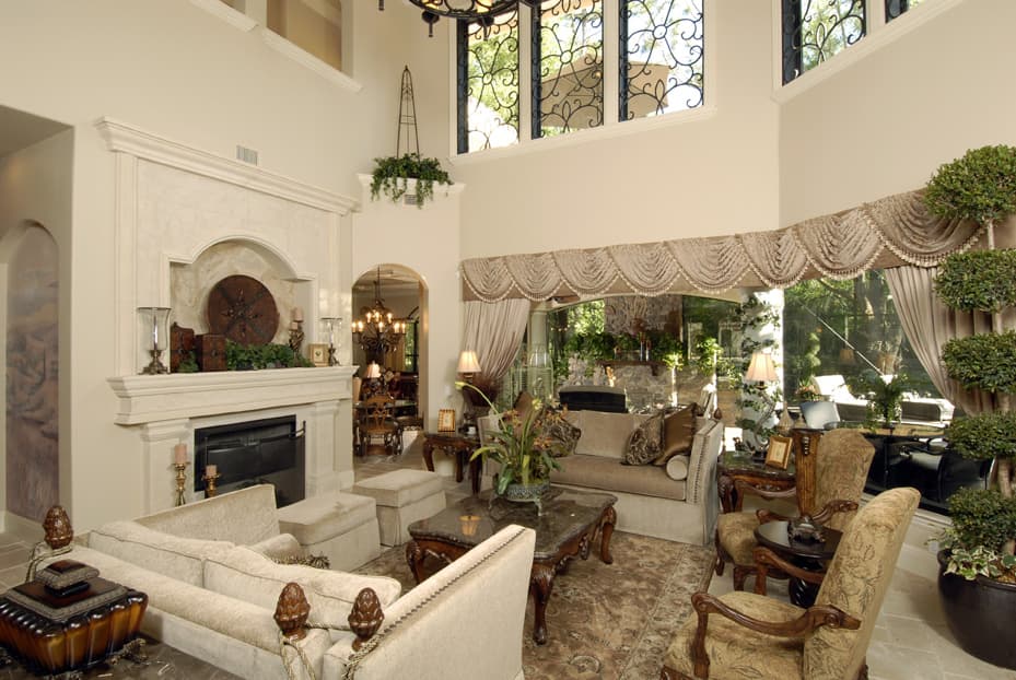 Great room with fireplace, arched doorway to dining, and large windows with ornate wrought iron.