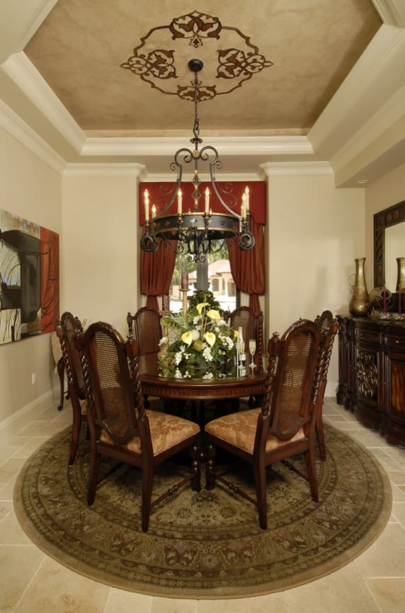 Interior rendering of a dining room with a round table, ornate chairs, buffet, and a tray ceiling with decorative molding.