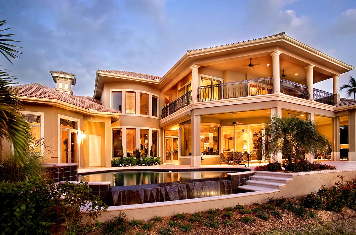 House plan exterior view of a two-story Mediterranean-style home with a tiled roof, arched windows, balconies, and an infinity pool.