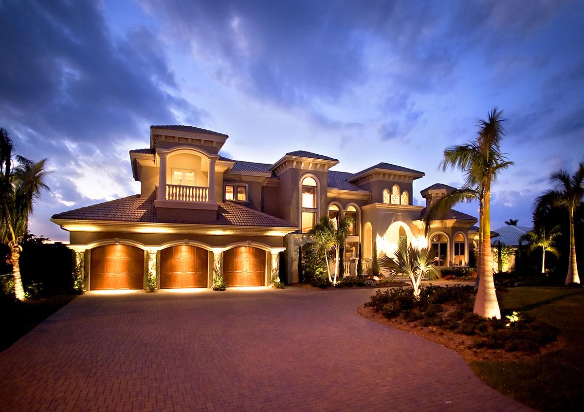 House plan exterior with four garage bays, a second-story balcony, arched windows, and tile roof.