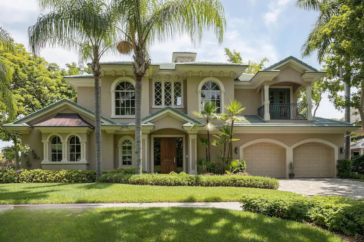 House plan exterior: two-story home with arched windows, prominent entrance, covered balcony, and a double garage.