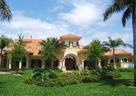 House plan exterior of a two-story Mediterranean style home with a tile roof, arched entryway, and numerous covered porches.