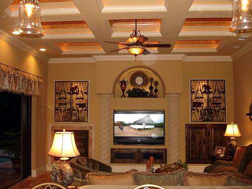 Interior view of a living room with coffered ceiling, fireplace, built-in cabinetry, and entertainment center.
