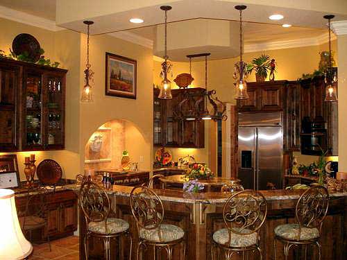 Kitchen interior with wood cabinetry, granite countertops, stainless steel refrigerator, and island with seating.