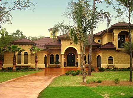 House plan exterior with Mediterranean style, arched entryway, multiple gables, and stucco finish.