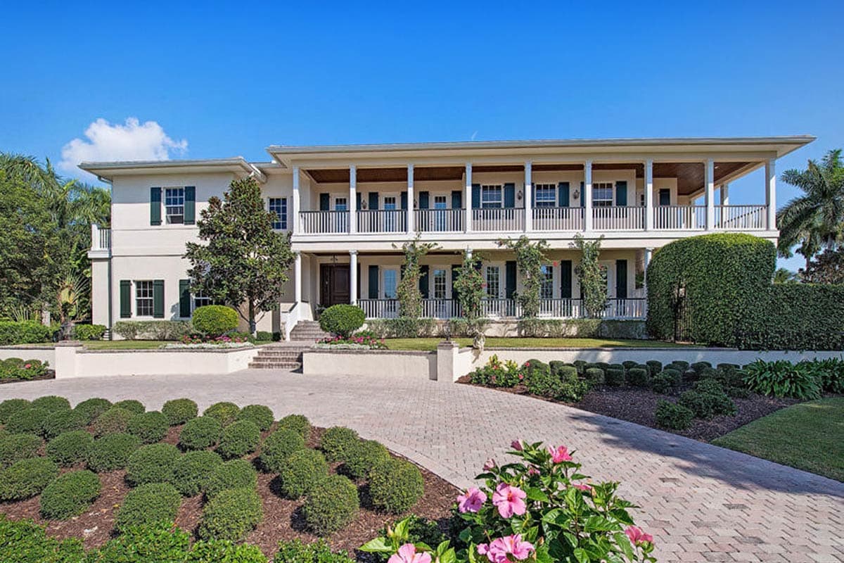 House plan exterior. Two-story with covered porch, second-story balcony, and symmetrical facade. Features include colonnades and shuttered windows.