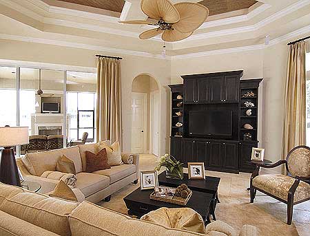 Living room with sofas, built-in entertainment center, and decorative ceiling fan. Archway leads to hallway.