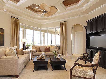 Living room with coffered ceiling, ceiling fan, large windows, and built-in entertainment center.