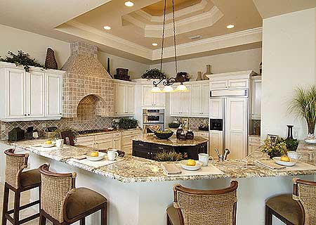 Kitchen with white cabinetry, island, granite countertops, and tiered ceiling with recessed lighting.