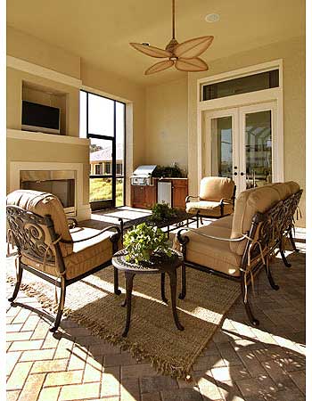 Covered patio with fireplace, outdoor kitchen, seating, and ceiling fan.