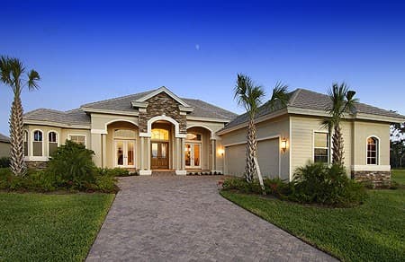 House plan exterior: one-story residence with arched entryway, stone accents, dual garage doors, and tropical landscaping.
