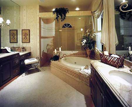 Bathroom featuring a sunken tub, dual vanities with marble countertops, and a glass-enclosed shower.