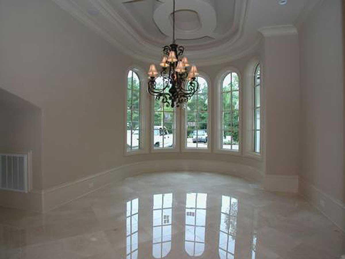 Interior view of a room with a large bay window, chandelier, and marble floors.