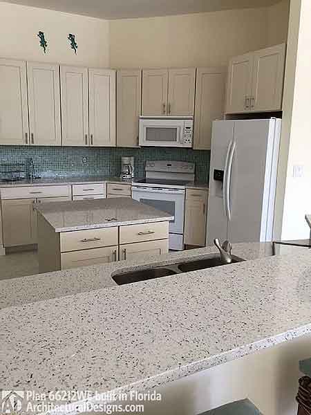Kitchen with granite island, light wood cabinetry, dual basin sink, and stainless steel appliances.
