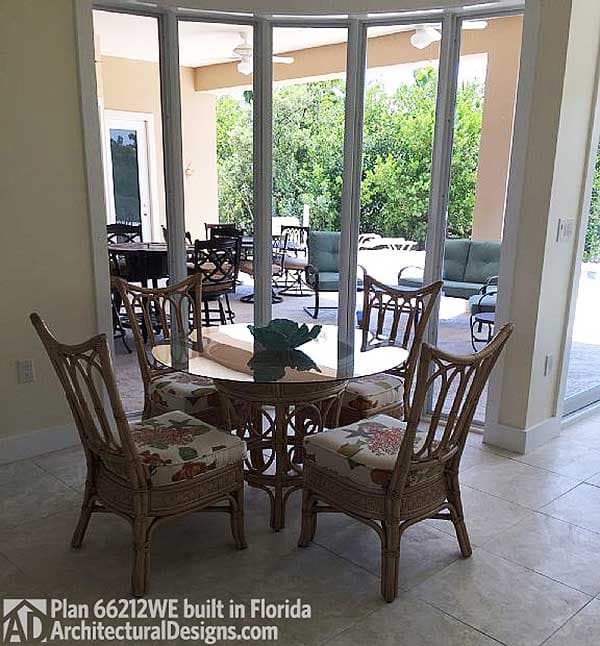 Indoor dining area with rattan furniture and glass-top table, opening to covered patio with outdoor seating.