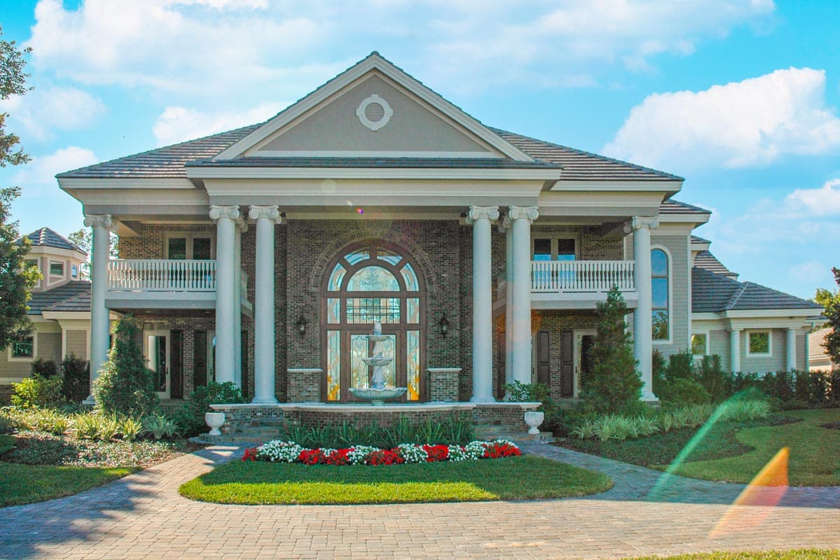 House plan exterior featuring a two-story design with a prominent portico, arched entryway, balconies, and classical columns.