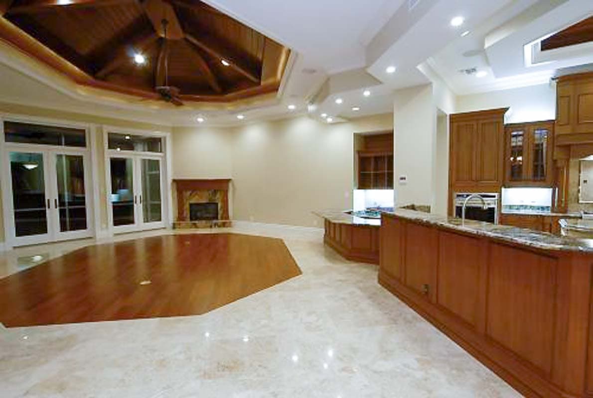 Interior rendering showing an open layout with wood-paneled ceiling, fireplace, and kitchen island with granite countertops.