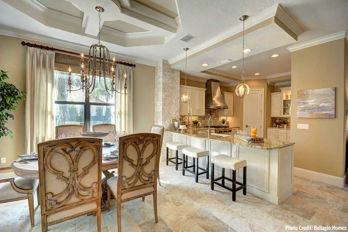 Open concept dining area and kitchen with island, decorative ceiling detail, and stacked stone accent wall.