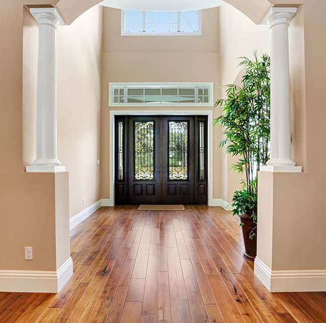 Interior view of a grand entryway with double doors, decorative glass, sidelights, transoms, and hardwood floors.