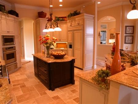 Kitchen interior with large island, double ovens, ample cabinetry, and arched doorway leading to another room.