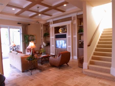 Interior view of a living area with a coffered ceiling, built-in entertainment center, and carpeted staircase.
