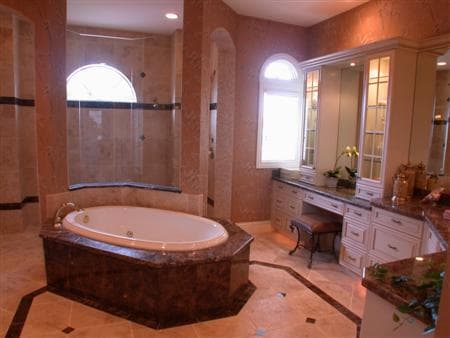 Master bathroom with a sunken jetted tub, glass-enclosed shower with arched window, and built-in vanity with mirrored cabinets.
