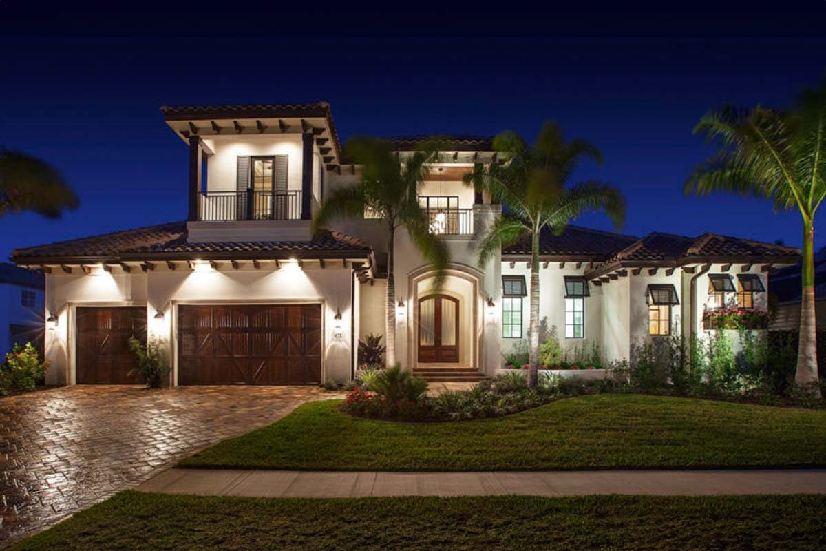 House plan exterior. Two-story Mediterranean style with a two-car garage, balconies, and a tile roof. Includes multiple gables and decorative trim.