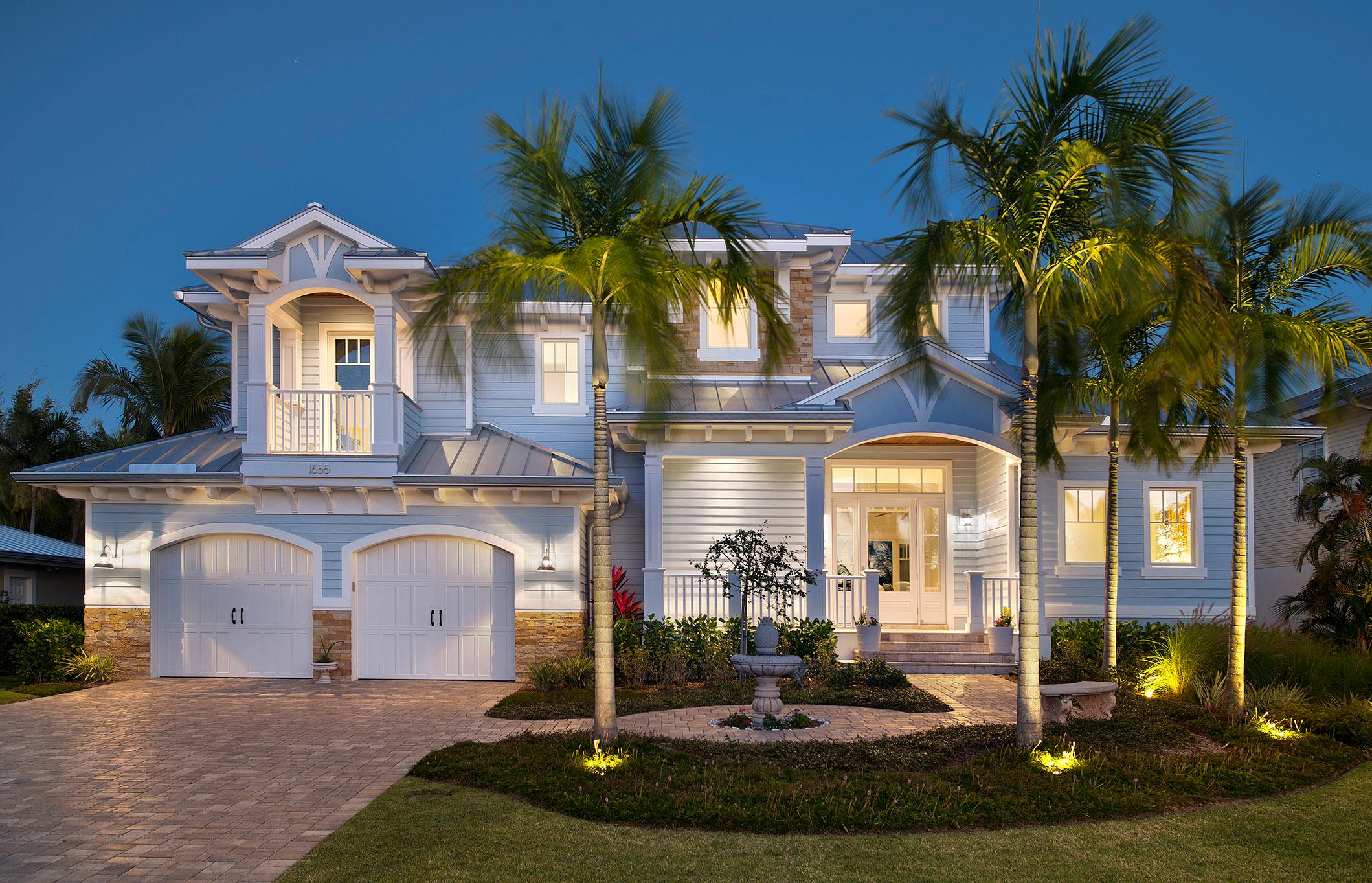 Coastal style house plan exterior with two stories, gabled dormers, balconies, metal roof, and a two-car garage.