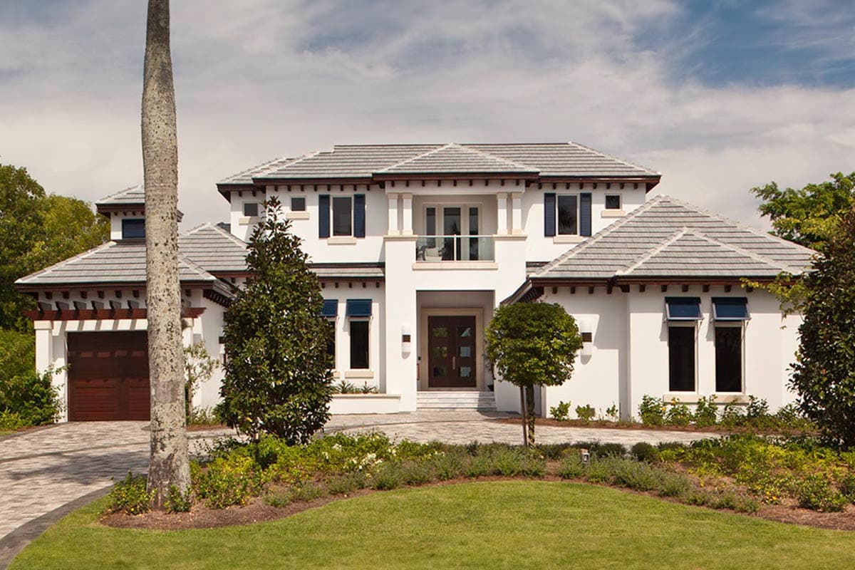 House plan exterior. Two-story Mediterranean style with a front balcony, multiple gables, and a porte-cochere with a detached garage.