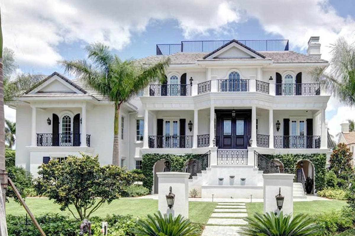 House plan exterior featuring a two-story design with balcony, black shutters, and wrought-iron railings. Includes a rooftop deck and formal entry.