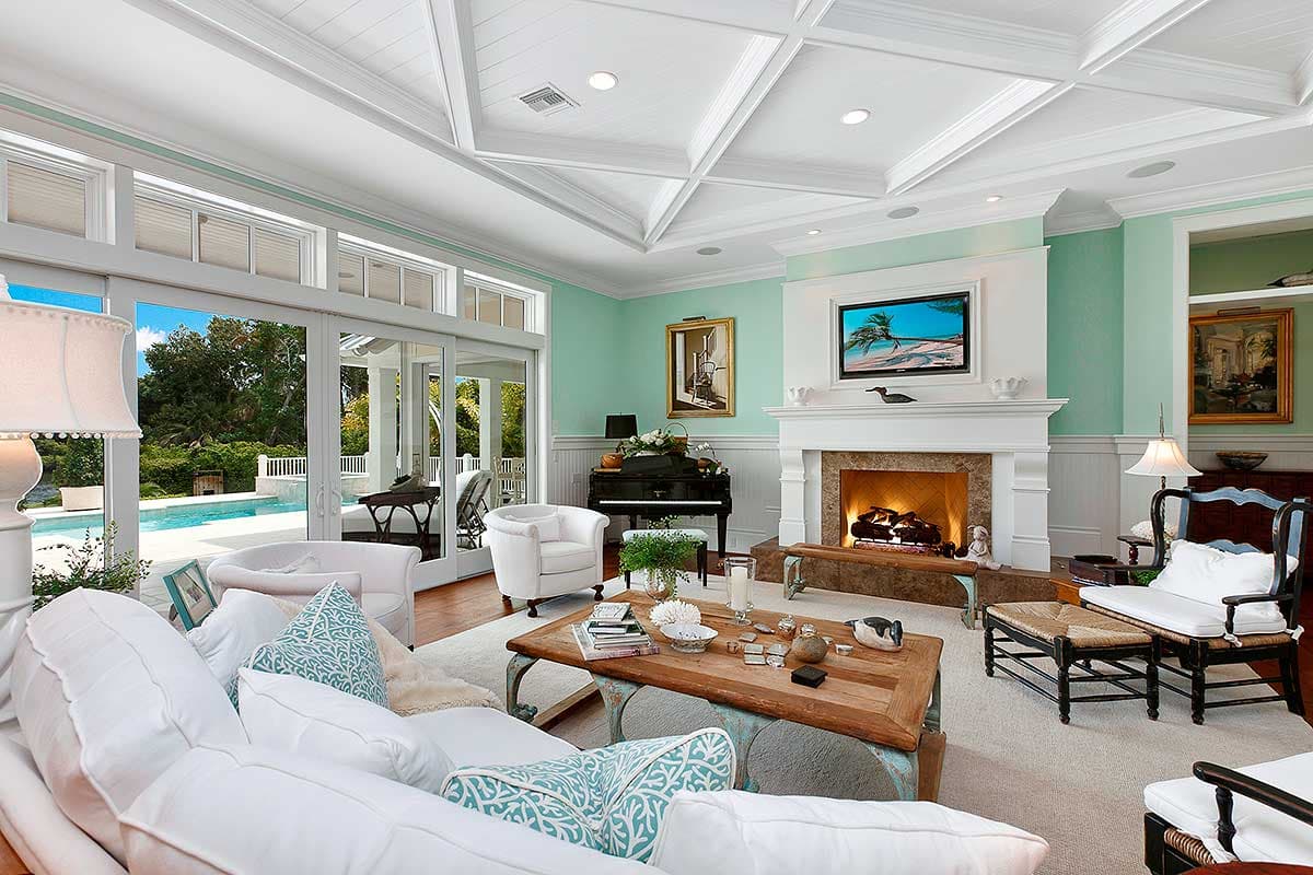Living room with fireplace, piano, and sliding glass doors opening to a pool area.