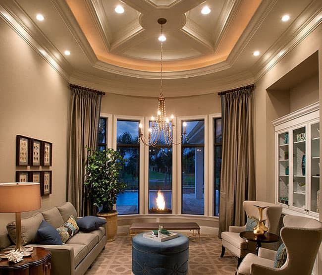 Living room with coffered ceiling, fireplace, bay windows, and built-in cabinetry.