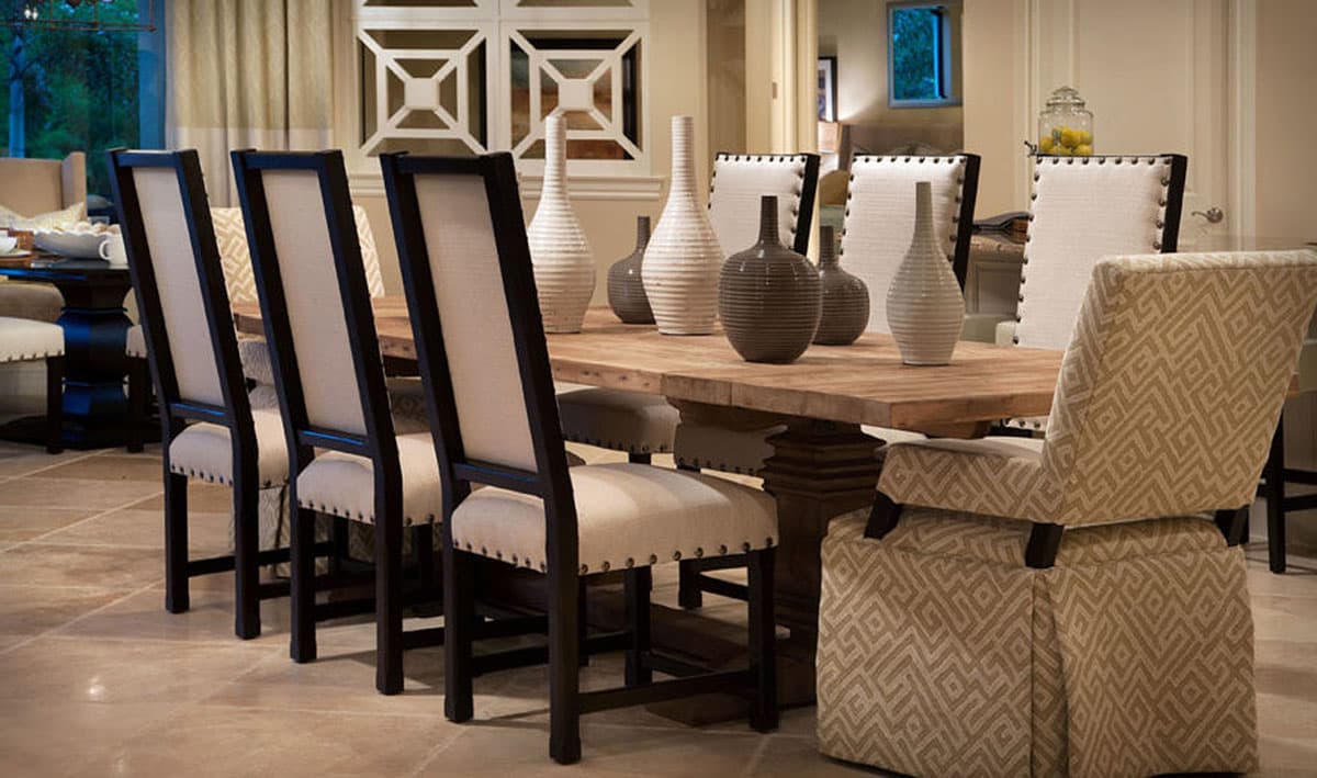 Interior view of dining room with a large wooden table, upholstered chairs, and decorative vases.