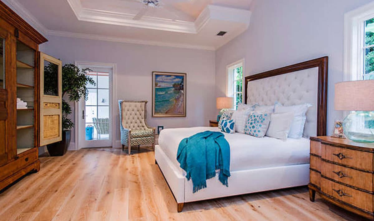 Bedroom featuring a tufted headboard, tray ceiling with fan, tall wood cabinet, and French doors leading outside.