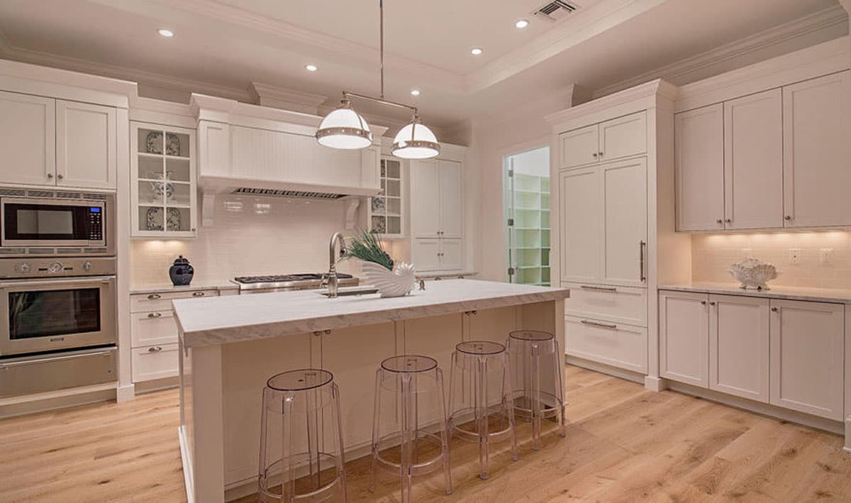 Kitchen with white cabinets, marble island, stainless steel appliances, and pendant lighting.