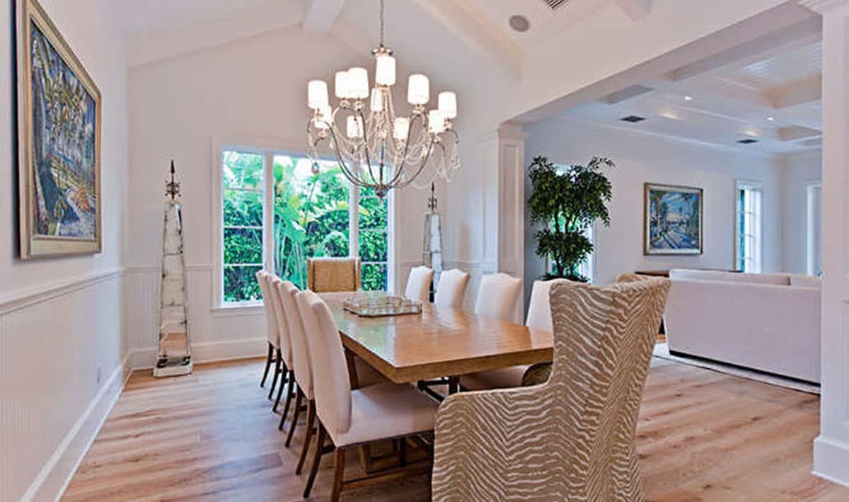 Dining room with vaulted ceiling, large table, and seating. Open view to living room.