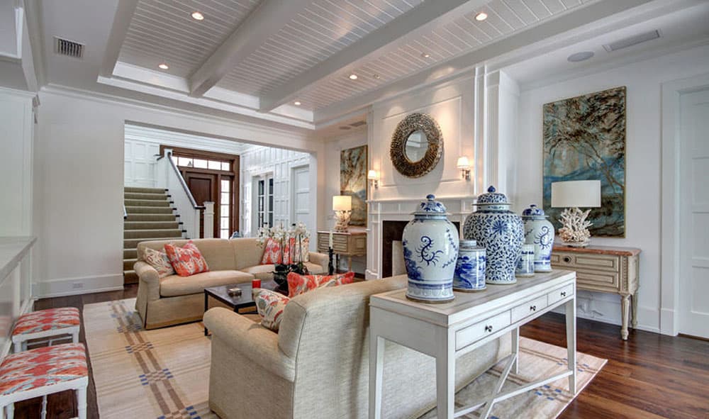 Great room with coffered ceiling, fireplace, staircase, and decorative vases.