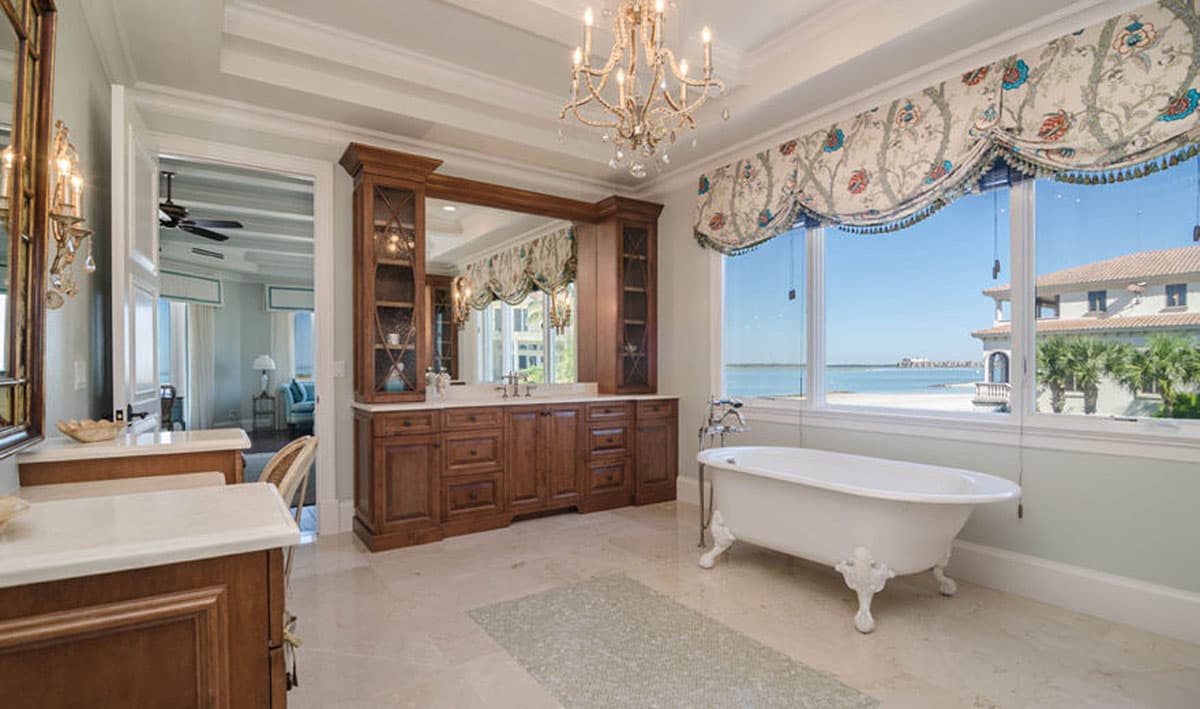 Bathroom with freestanding tub, double vanity, built-in cabinetry, and ocean view.