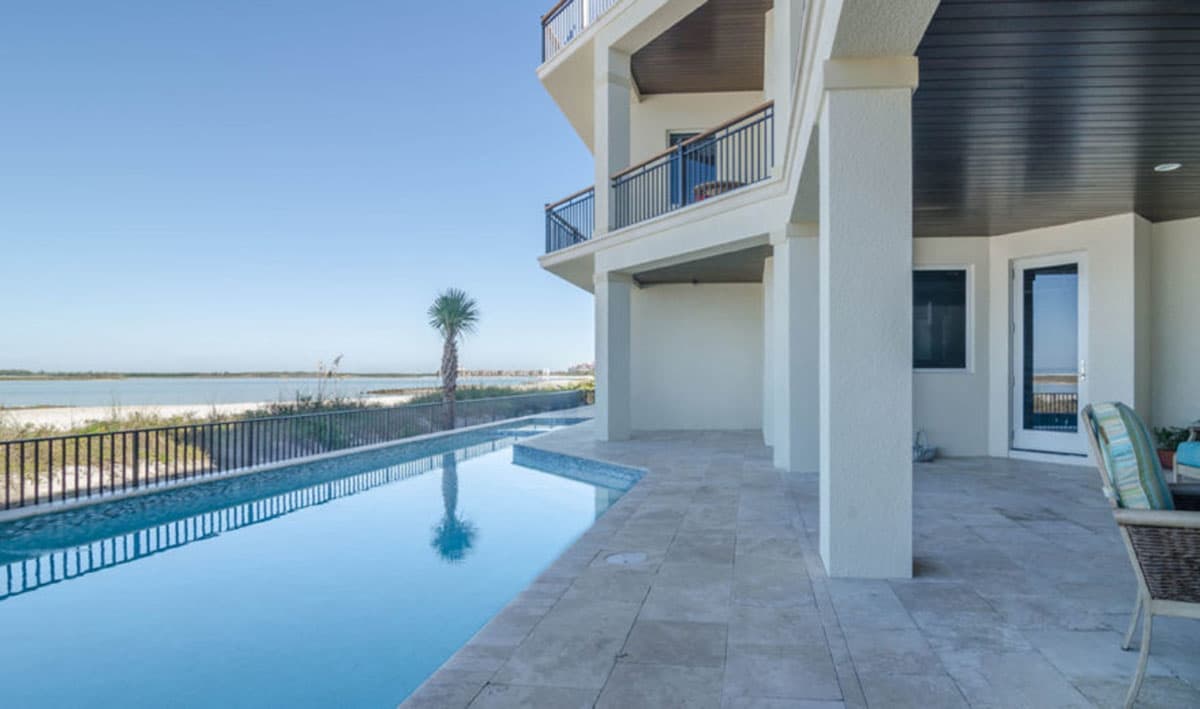 House plan exterior with multiple balconies, a covered patio, and an infinity pool overlooking the water.