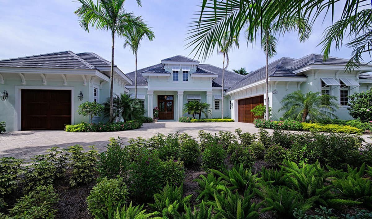 House plan exterior. Two-story, coastal style. Features include multiple gabled roofs, shutters, and attached garages on either side of the entry.