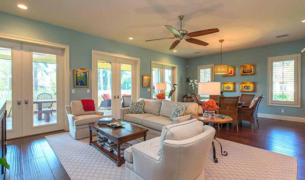 Living room with sofas, coffee table, and dining area. French doors open to a screened porch.
