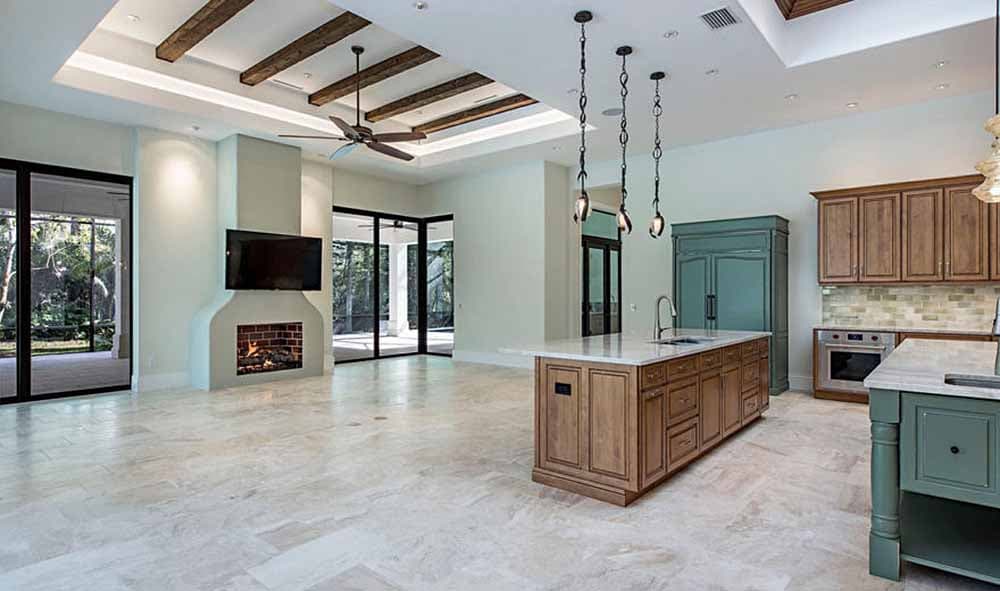 Spacious open-concept kitchen and living area with coffered ceiling, exposed beams, fireplace, and island.