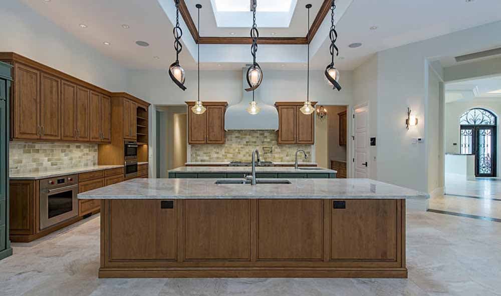 Spacious kitchen with a large island, wood cabinetry, dual sinks, and decorative pendant lighting above.