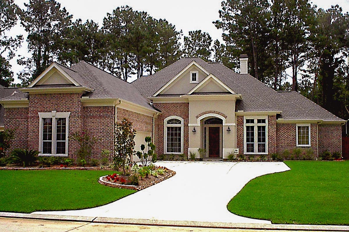 House plan exterior of a one-story brick home with a pitched roof, arched entryway, prominent gables, and a side-entry garage.