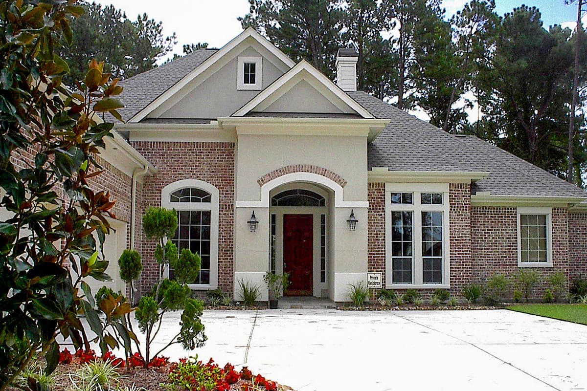 House plan exterior: Traditional style home with arched entryway, brick facade, gable dormer, and multiple windows.