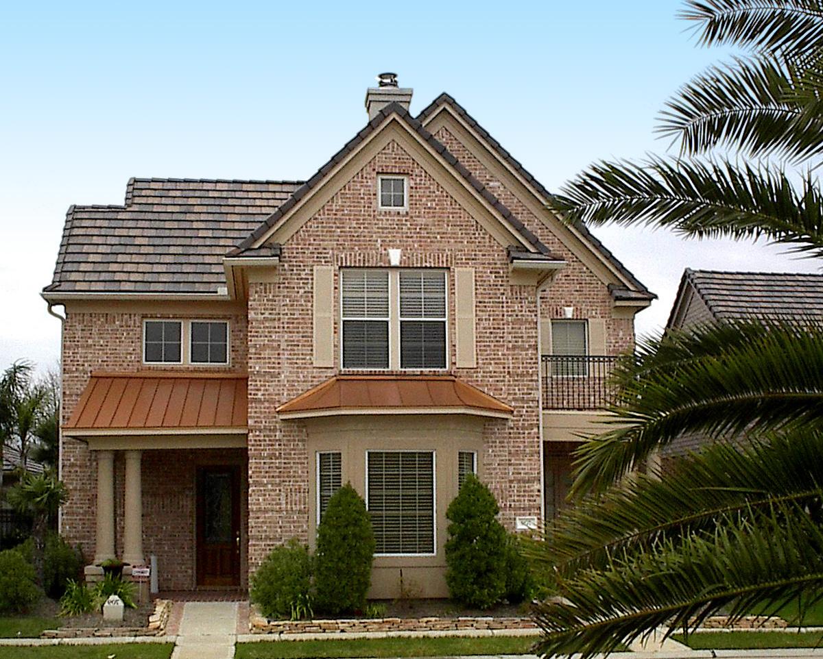 House plan exterior: Two-story brick home with a gable roof, copper awnings, a covered porch, and a balcony.