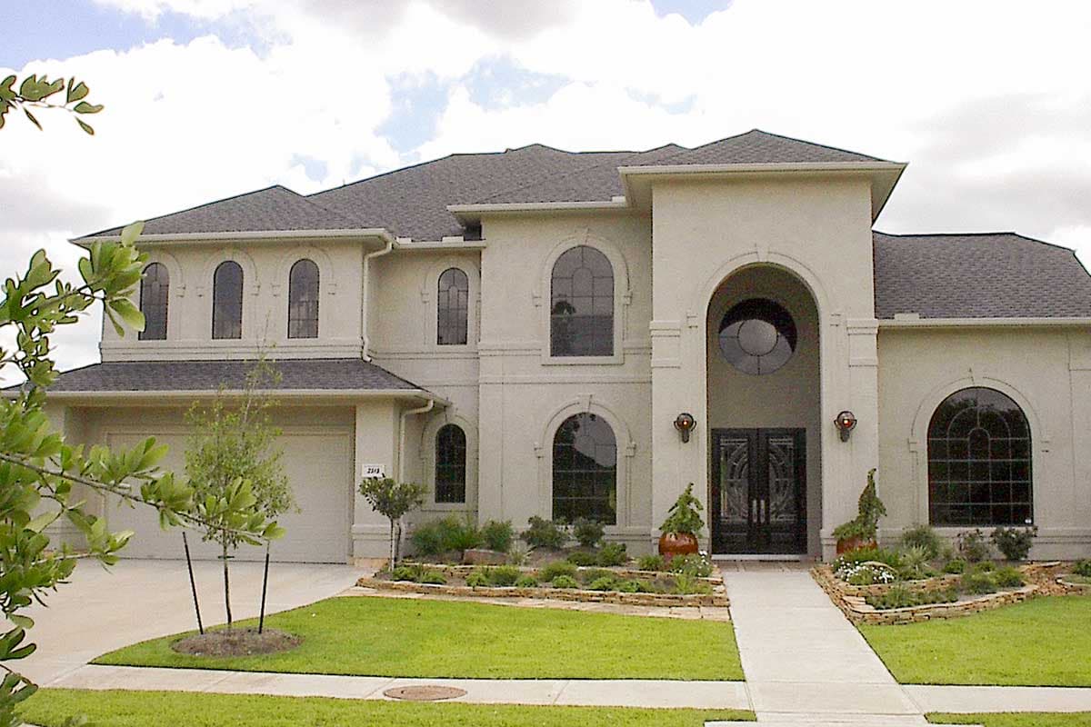 House plan exterior of a two-story stucco home with a prominent arched entryway, multiple arched windows, and a side-facing garage.