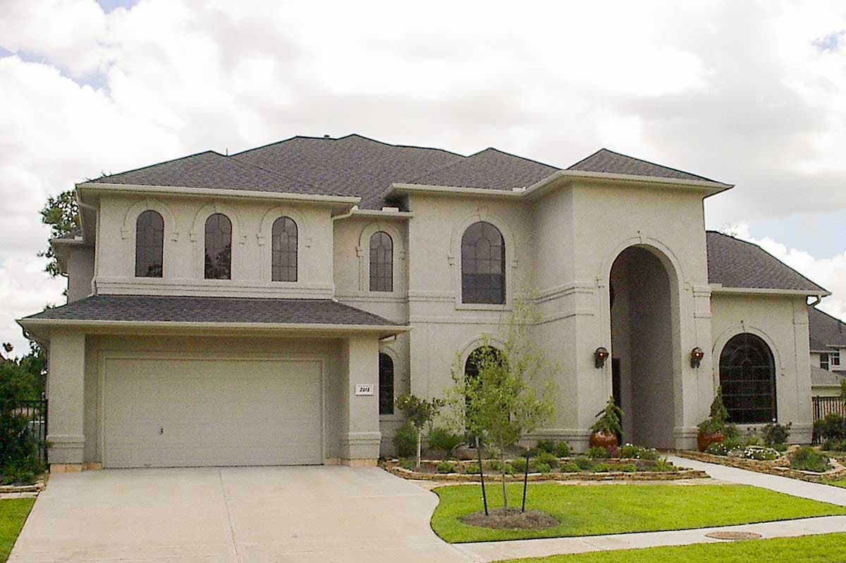 House plan exterior: two-story stucco residence with a three-car garage, arched windows, and a grand arched entryway.