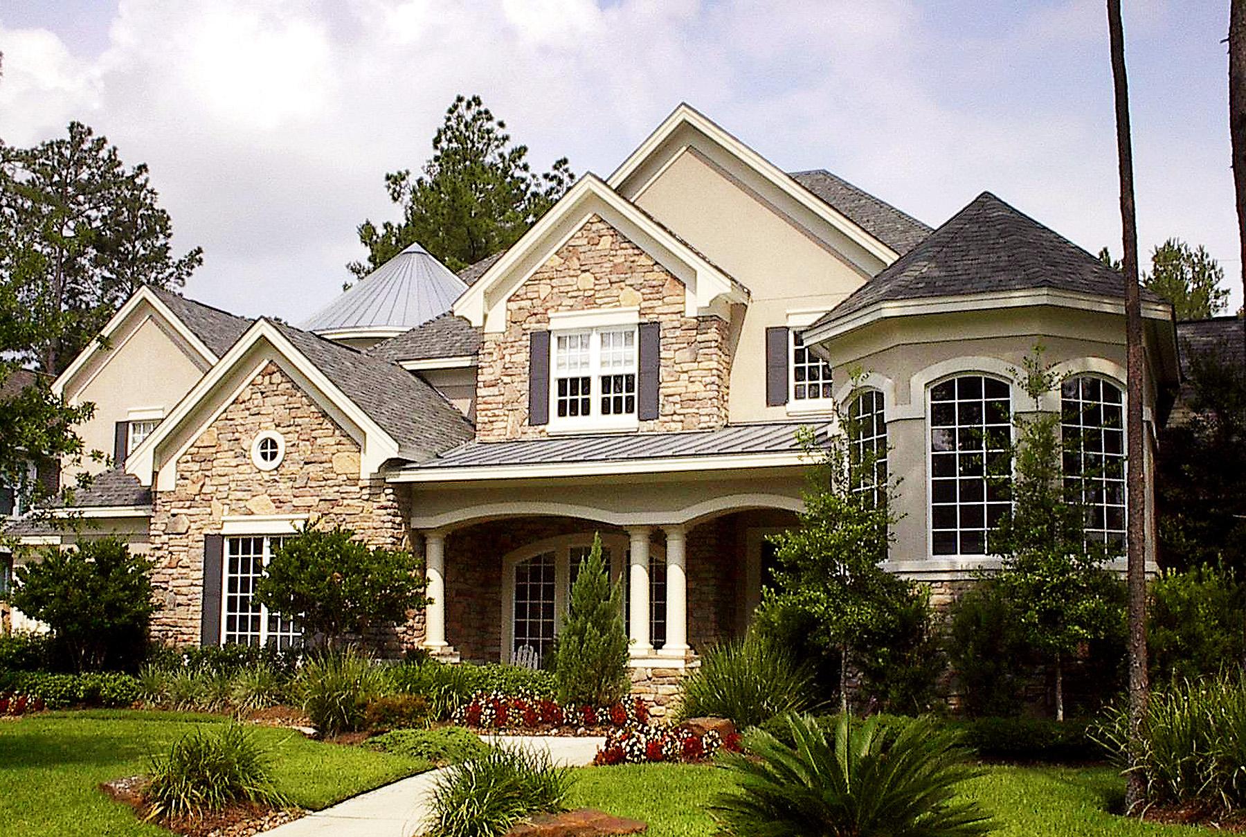 House plan exterior with stone accents, covered porch supported by columns, gables, dormers, and a bay window.